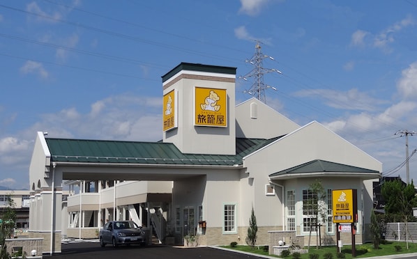 A hotel with a green roof, a sign with a bear, and a car parked in front. - Family Lodge Hatagoya Tsuyama (Tsuyama)