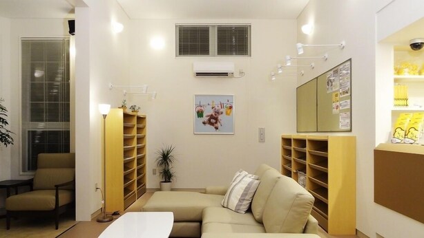 Una sala de estar con un sofá, una mesa de centro, una estantería y un aire acondicionado instalado en la pared.