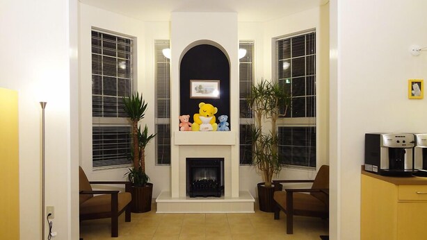 A living room with a fireplace, two chairs, a coffee machine, and a bear statue. - Family Lodge Hatagoya Niihama (Niihama)