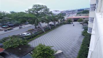 A courtyard with a patterned floor, surrounded by trees and a building.