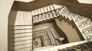 A spiral staircase with a wooden finish and decorative metal railings. - Hotel Sheetal Regency (Mathura)