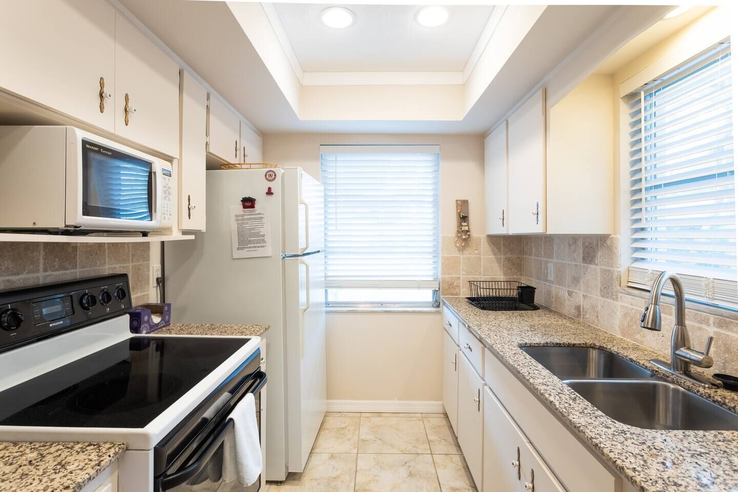 A compact kitchen with a microwave, stove, oven, and granite countertops.