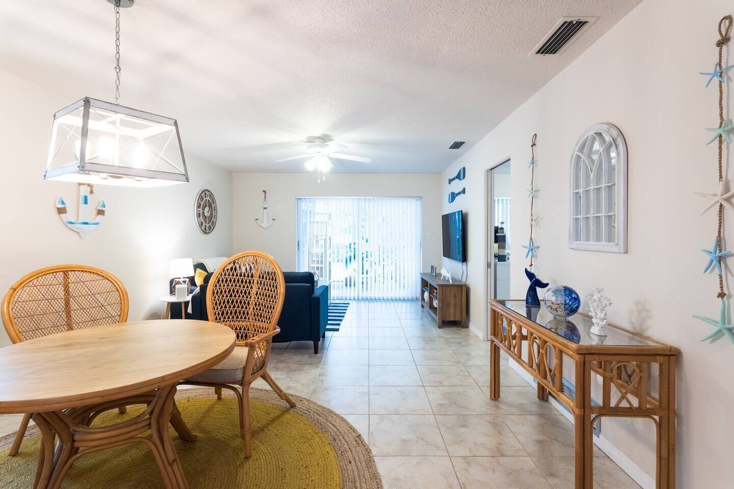 A spacious living area with a dining table, chairs, a TV, and a balcony with a view.