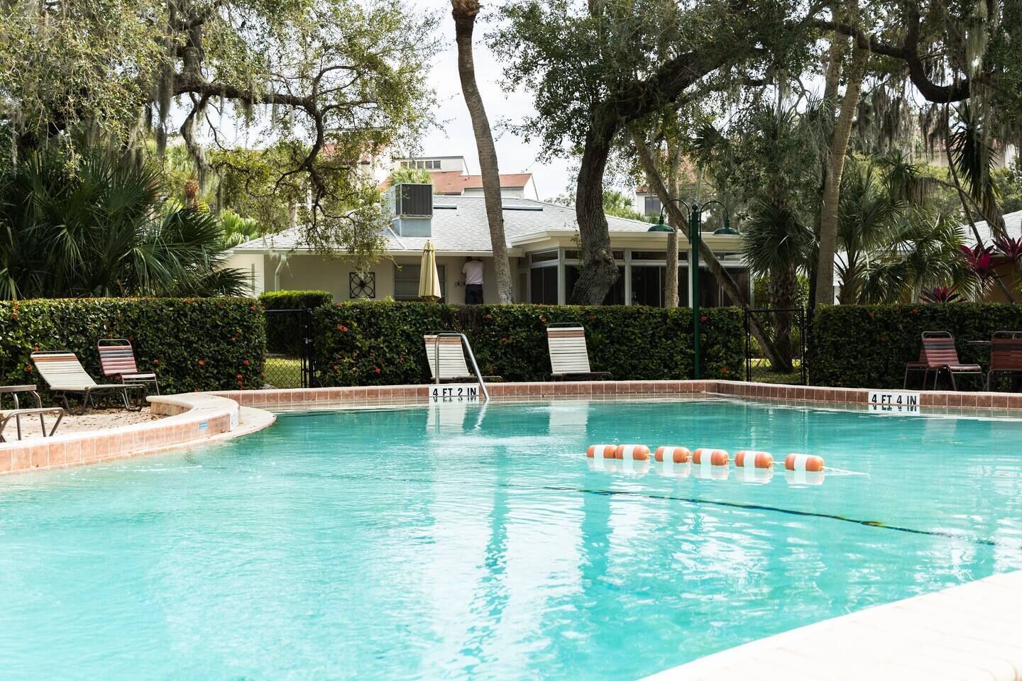 A swimming pool with a 4 ft 2 in depth, surrounded by lounge chairs and palm trees.