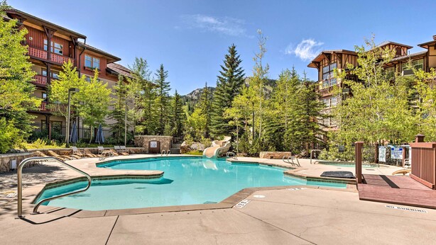 A pool area with a water slide, lounge chairs, and a wooden deck. - Solitude Mountain Resort Condo at Lift Base! (Solitude)