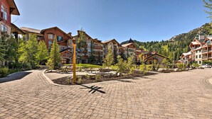 A paved courtyard with a picnic area, surrounded by multi-story buildings with balconies and a mountainous backdrop. - Solitude Mountain Resort Condo at Lift Base! (Solitude)