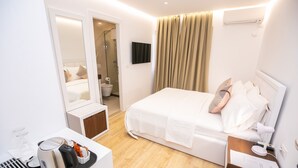 A modern hotel room with a bed, bedside table, and a small desk with a kettle and glasses. - Hotel Elior  (Tirana)