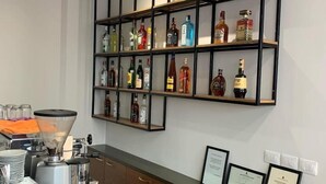 A bar area with shelves of liquor bottles, a coffee machine, and a counter with a coffee pot. - Hotel Elior  (Tirana)