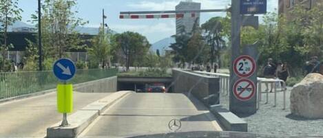 A view from inside a car, looking out through the windshield at a road with a pedestrian crossing and a barrier gate.
