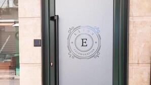 A door with a frosted glass panel and a logo with the letter 'E' in the center. - Hotel Elior  (Tirana)