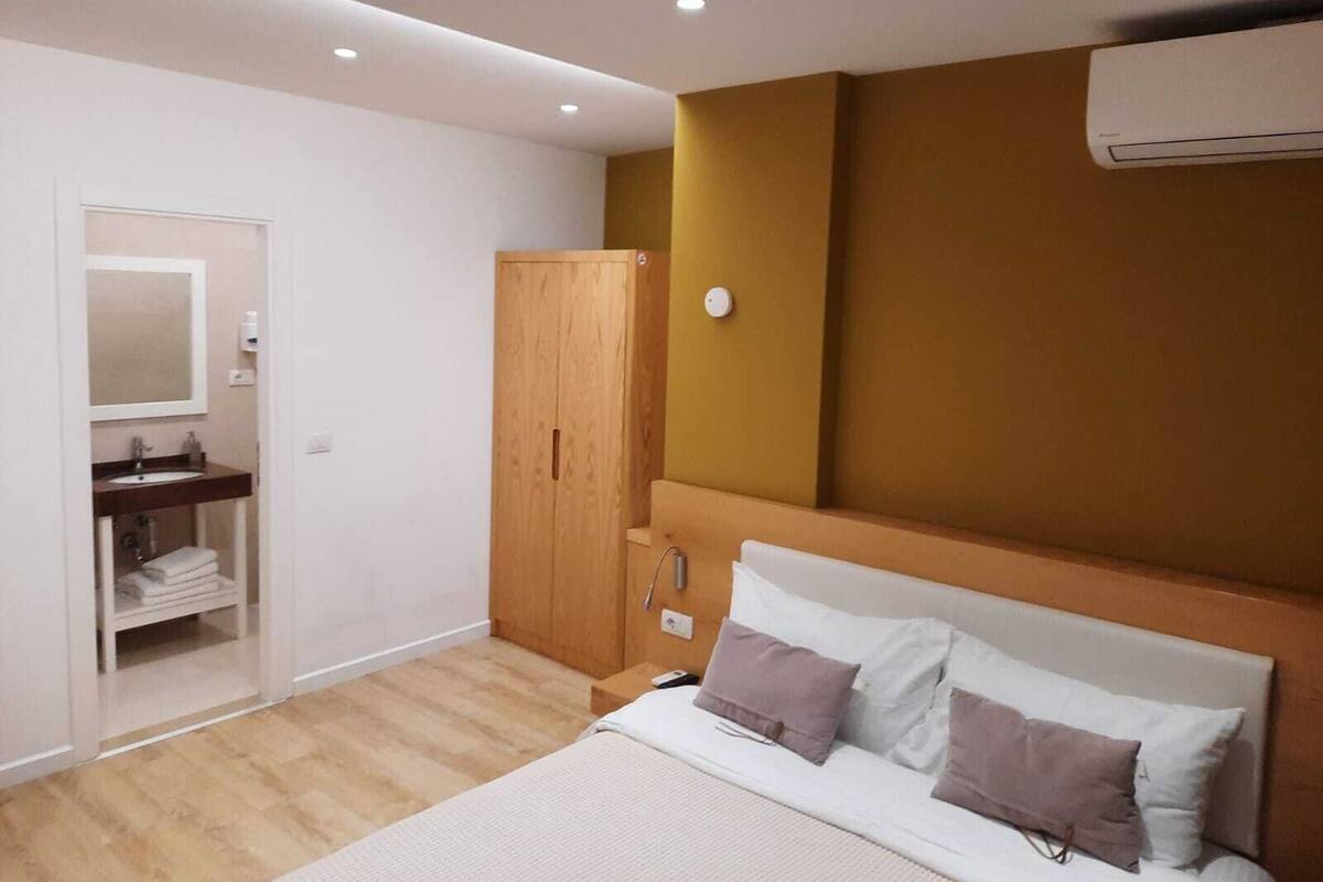 Un dormitorio moderno con un armario de madera, una mesita de noche y una cama con almohadas.