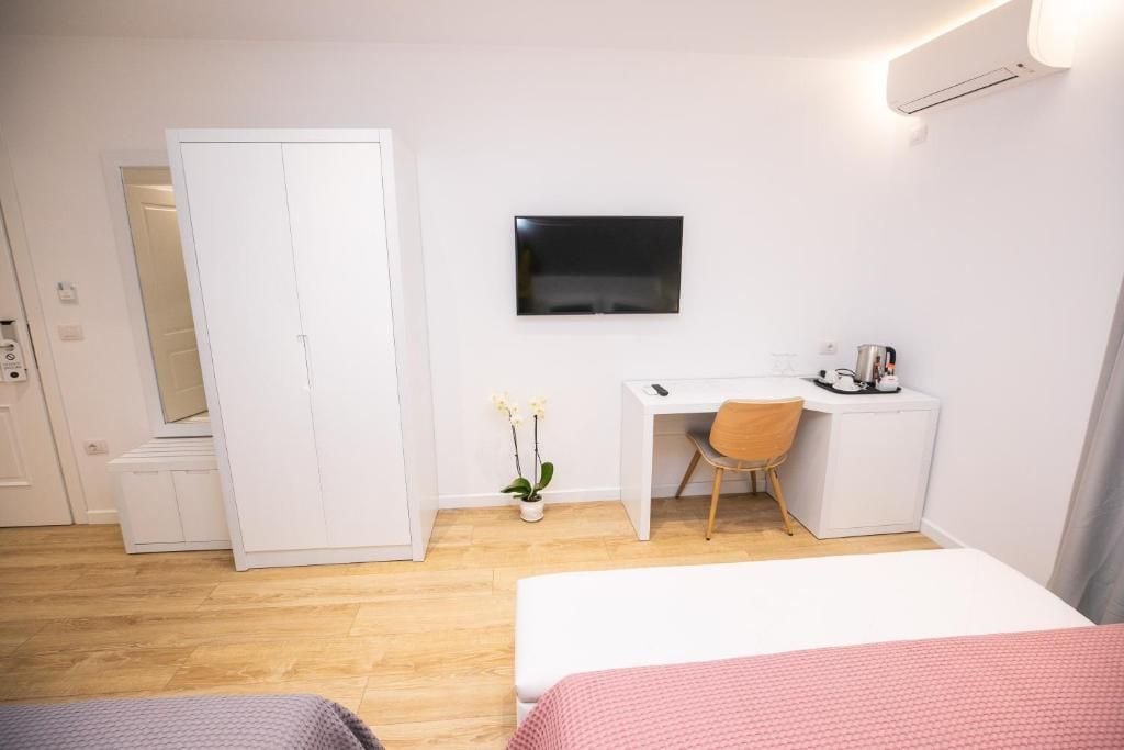 Een hotelkamer met een bed, een bureau, een stoel, een kledingkast en een televisie aan de muur.