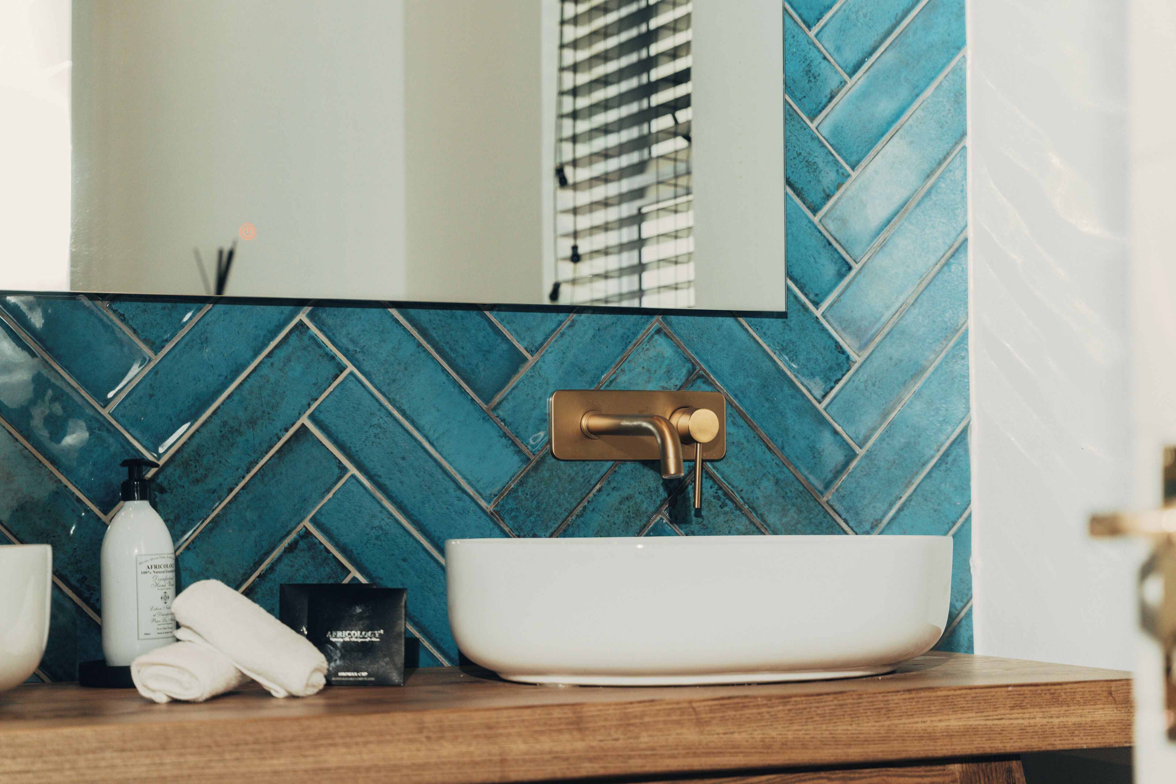 Un baño con un lavamanos blanco, un espejo y un salpicadero con un estampado azul de tablero de ajedrez.