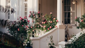 A white building with a covered porch, columns, and a staircase leading to a door. - Les Chambres (Franschhoek)