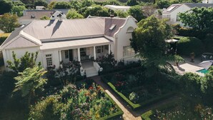 A large, white, two-story house with a covered porch and a swimming pool in the backyard. - Les Chambres (Franschhoek)
