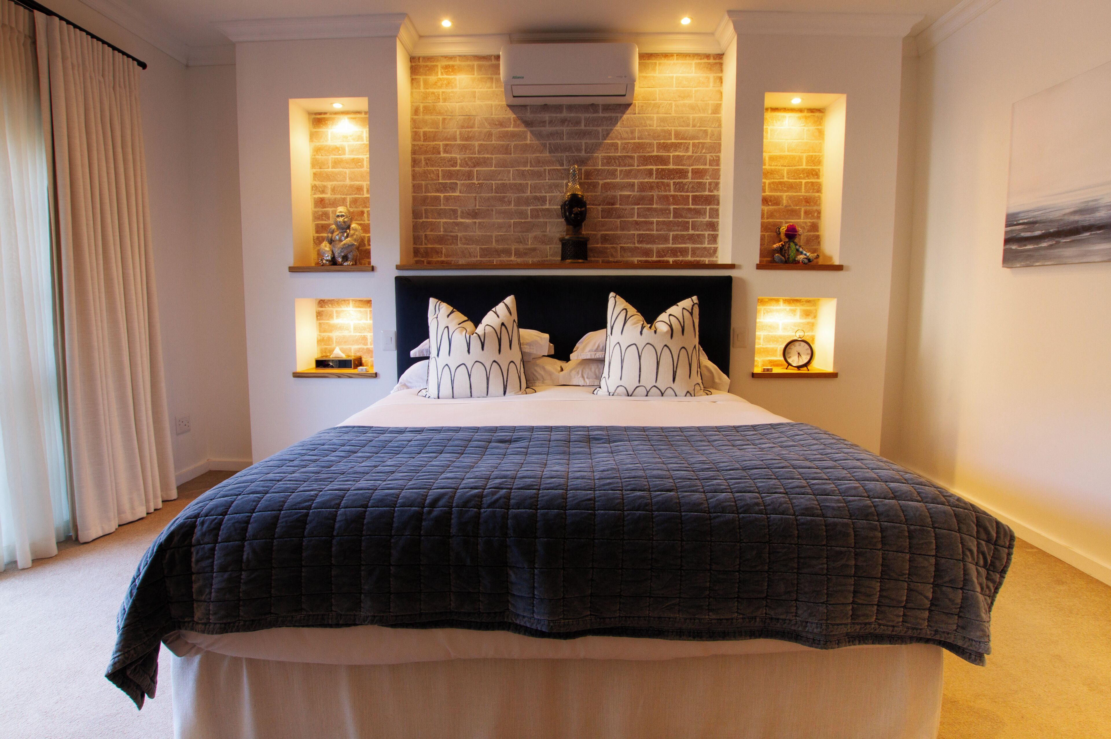 A bedroom with a large bed, a brick wall, and two wall-mounted lights.