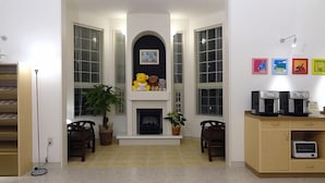Una sala de estar acogedora con chimenea, dos sillones, una estación de café y una estantería.
