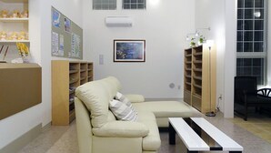 Una sala de estar con un sofá color crema, una mesa de centro blanca y una estantería.