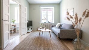 A modern living room with a grey sofa, a coffee table, and a vase with dried plants. - Roost Eerikinkatu (Helsinki)