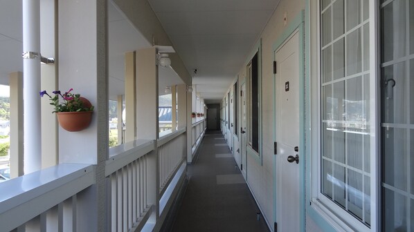 A corridor with a white railing, potted plants, and doors with numbers. - Family Lodge Hatagoya Shimanto (Shimanto)