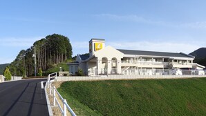 Een gebouw met twee verdiepingen, een witte gevel en een geel bord op de hoek.