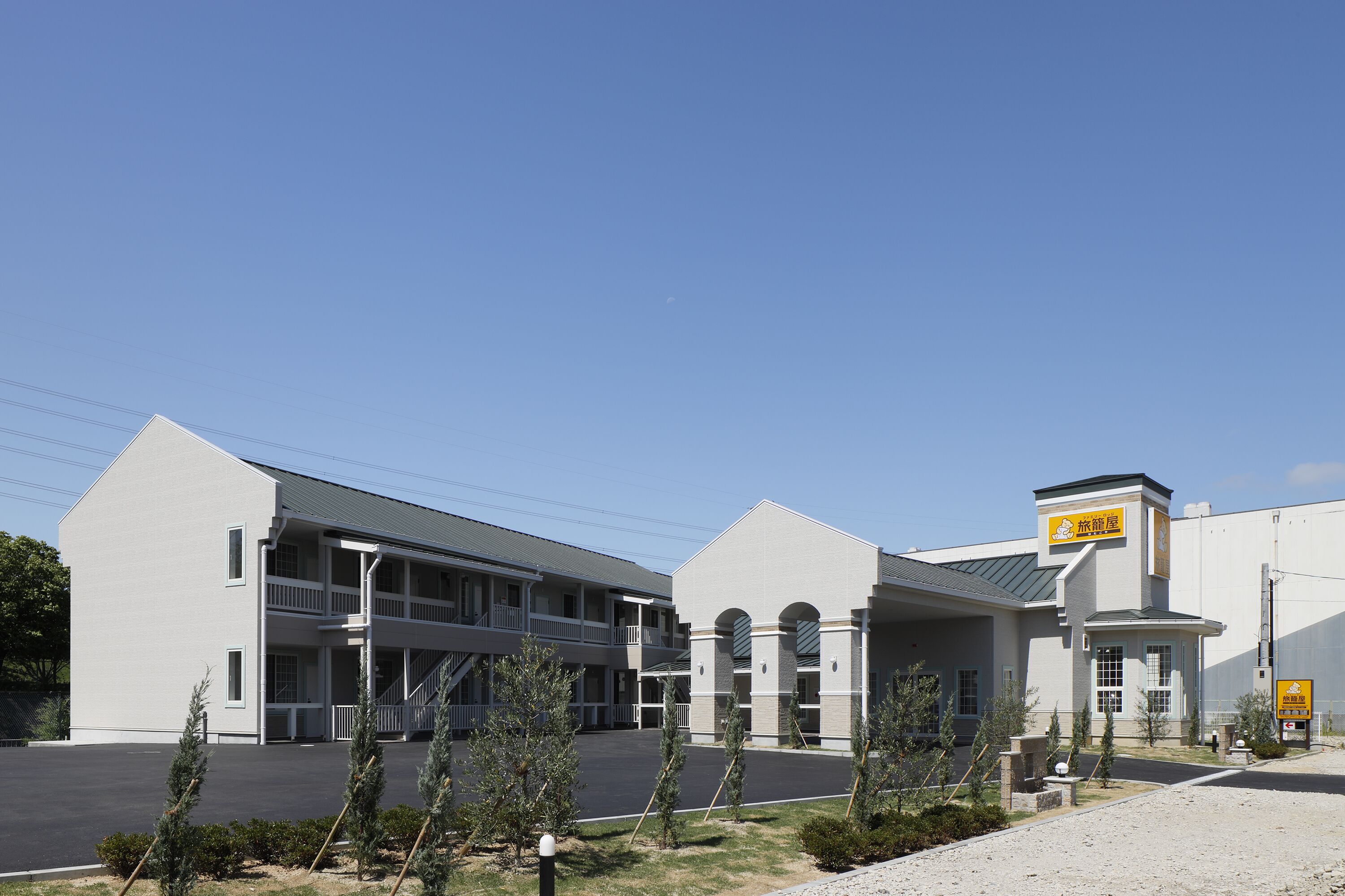 A two-story motel with a central courtyard, a sign indicating a restaurant, and a parking lot.