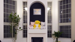 Una sala de estar con chimenea, tres osos de peluche y dos macetas.