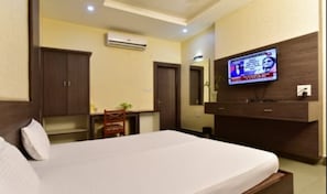 A hotel room with a bed, a desk, a chair, a TV, and a wardrobe. - Silver Inn (Bhopal)