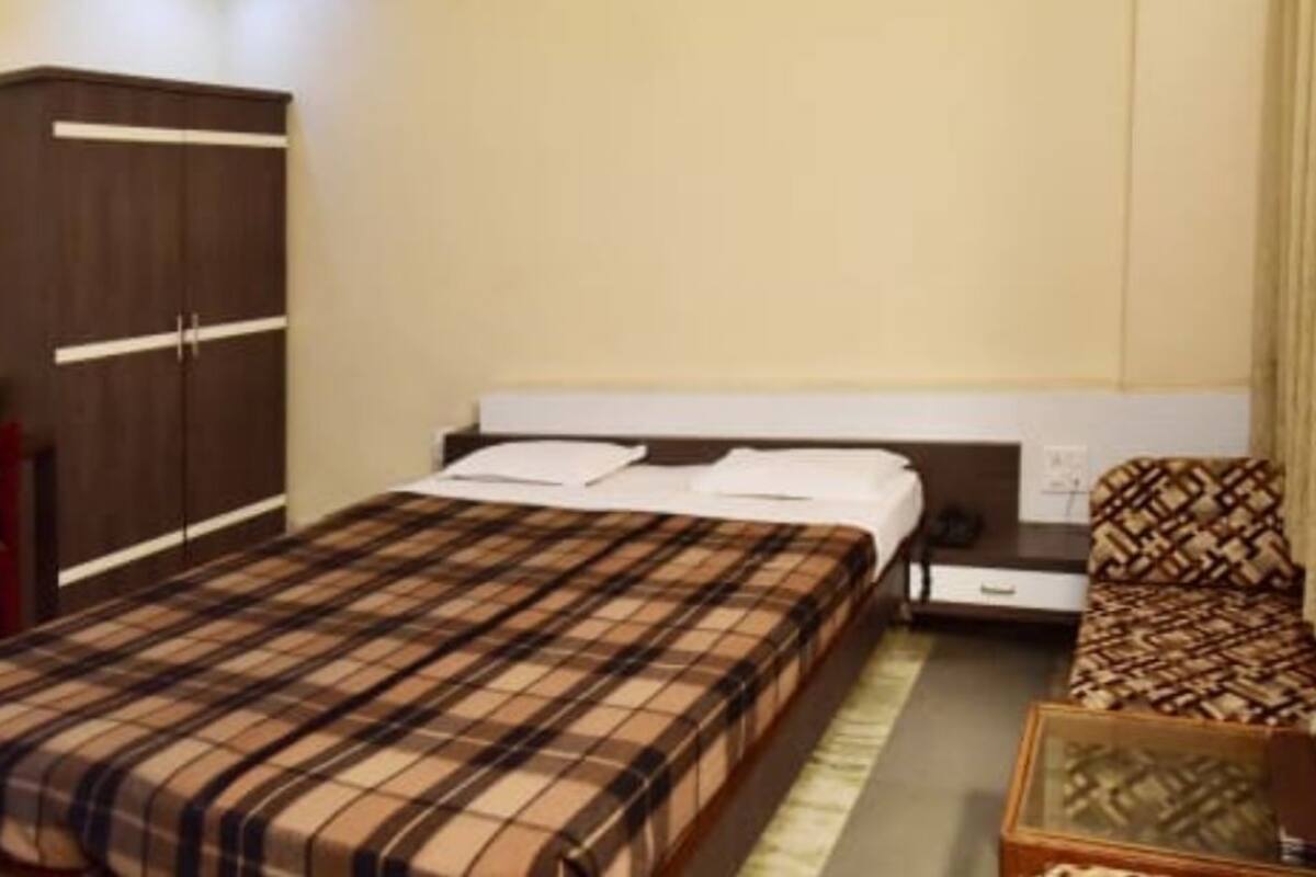 A bedroom with a bed, a wardrobe, a chair, and a bedside table.