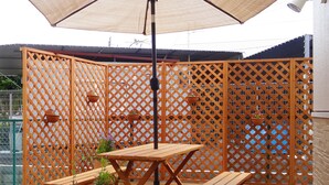 Een houten terras met een tafel en bankje, omringd door een lattenhek.