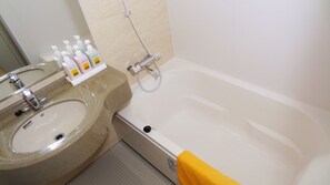 Een badkamer met een wastafel, spiegel en bad. Er staan toiletartikelen op het aanrecht.