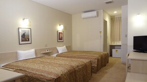Een hotelkamer met twee bedden, een bureau, een televisie en een airconditioning.