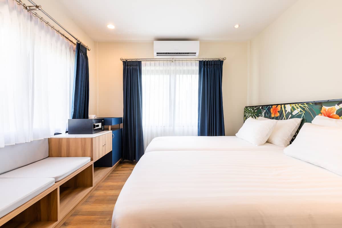Habitación de hotel con cama, escritorio, silla y ventana con cortinas.