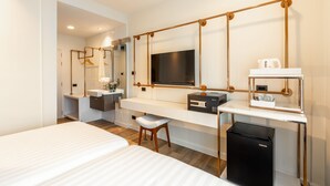 Quarto de hotel moderno com uma cama grande, uma mesa com televisão de tela plana, um mini-refrigerador e uma toucador com espelho.