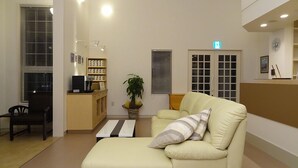 Een ontvangsthal met een bank, een koffiehoekje, een plant en een receptiebalie.