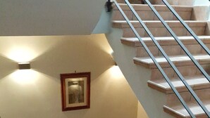 Un escalier muni d’une rampe, un tableau encadré accroché au mur et un luminaire placé au-dessus.
