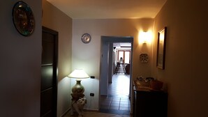 Un couloir avec une lampe, une assiette décorative et une échelle en arrière-plan.