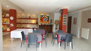 Un coin repas avec une table et des chaises, une horloge au mur et des étagères remplies de divers objets.