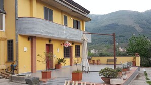 Un bâtiment jaune avec une enseigne indiquant « Tico » et un balcon orné de plantes en pot.