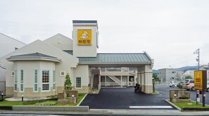 A building with a yellow sign featuring a bear, a covered entrance, and a parked motorcycle. - Family Lodge Hatagoya Okayama (Okayama)