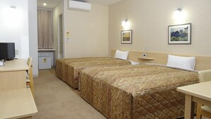 A hotel room with two beds, a desk, a chair, a small table, and a TV. - Family Lodge Hatagoya Matsuyama (Matsuyama)