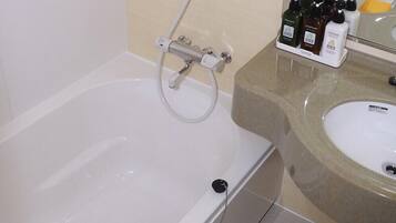 Un bagno con vasca, lavandino e doccia. Sul piano del lavandino ci sono articoli da toilette.