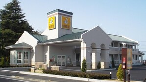 A building with a white exterior, a green roof, and two yellow signs with a cartoon bear. - Family Lodge Hatagoya Matsuyama (Matsuyama)