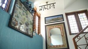 A room with a large framed photo collage, a decorative mirror, and a window with a view of a landscape. - Dev Vatika Home Stay (Gurugram)