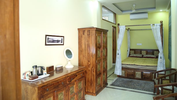 A bedroom with a wooden dresser, a bed with a canopy, and a ceiling fan. - Dev Vatika Home Stay (Gurugram)