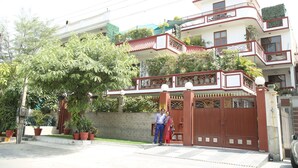 A multi-story residential building with a gated entrance, potted plants, and a balcony. - Dev Vatika Home Stay (Gurugram)
