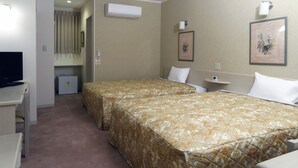 A hotel room with two beds, a TV, a mini-fridge, and a small desk.