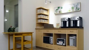 A kitchenette with a microwave, coffee maker, and storage cabinets.