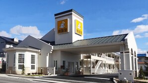 A hotel with a prominent tower, a covered entrance, and a two-story structure with balconies.
