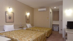 A hotel room with two beds, a desk with a television, an air conditioner, and framed artwork on the walls. - Family Lodge Hatagoya Sanuki Kanonji (Kanonji)